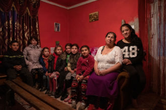 Ukrainalainen Vera istuu pienen kotinsa sängyllä lastensa ja lastenlastensa kanssa.