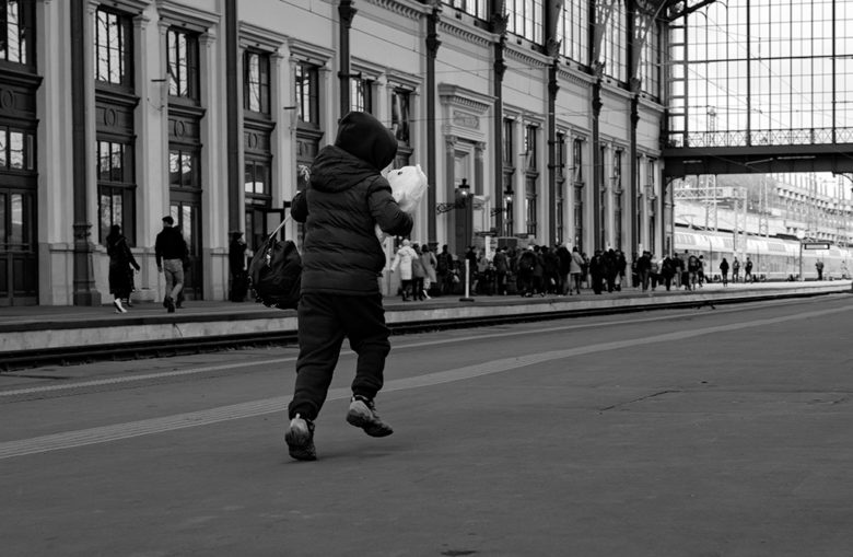 Pieni poika juoksee nallen kanssa rautatieasemalla.