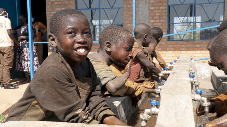 Iloisia lapsia juomassa vesipisteestä.