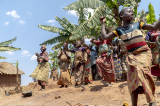 Burundilaiset naiset tanssivat iloisesti palmujen alla.