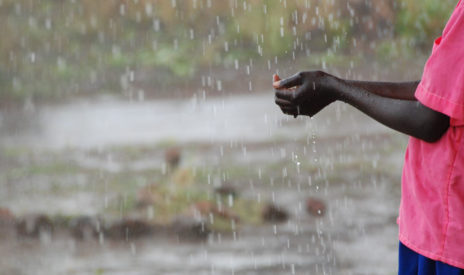 Vesisade, lapsen kädet näkyvät kourassa keräille sadepisaroita