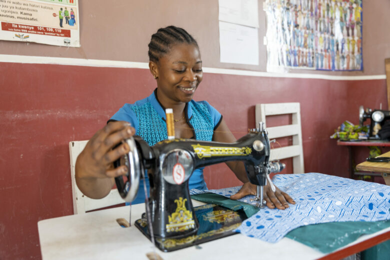 ASAM-järjestön ompelukurssille osallistuva nuori nainen ompelee sinistä kangasta.
