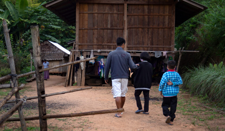 Lapset kävelevät kotipihaansa, jossa on iso puinen rakennus.