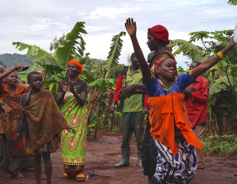 Rutambwen kylän asukkaita laulamassa ja tansimassa banaanipuiden lomassa.